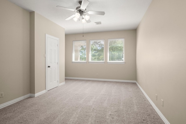 carpeted spare room featuring visible vents, baseboards, and ceiling fan