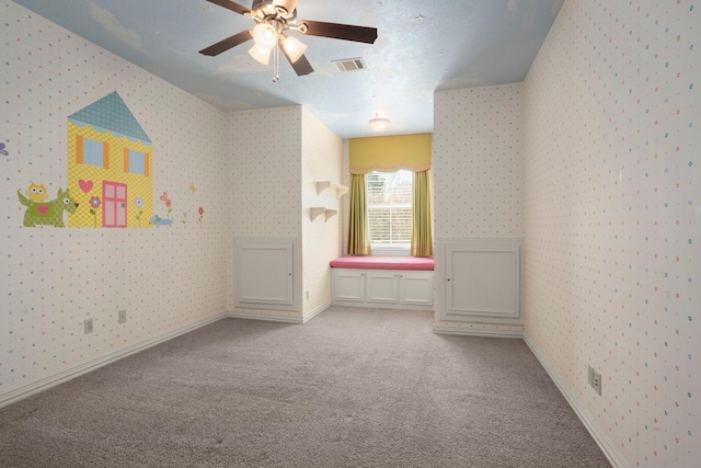 carpeted empty room featuring visible vents, baseboards, a ceiling fan, and wallpapered walls