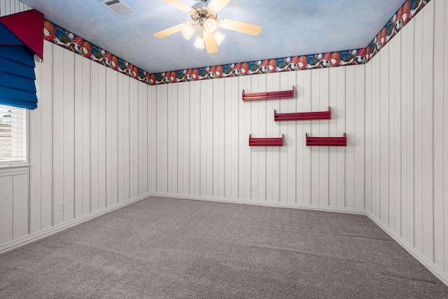 carpeted spare room featuring visible vents and ceiling fan