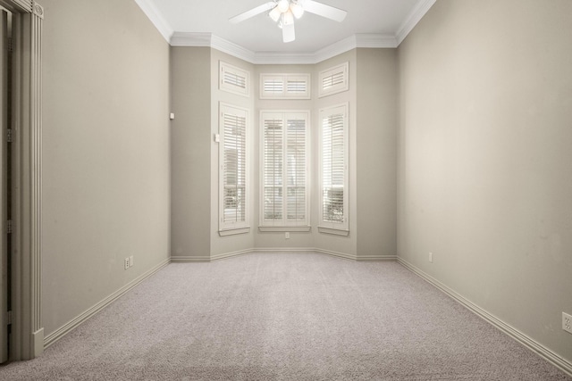 carpeted spare room with baseboards, ceiling fan, and crown molding