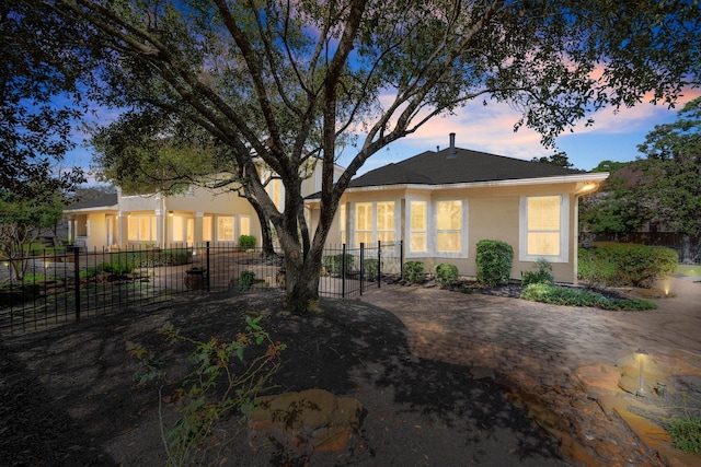 rear view of house featuring stucco siding and fence