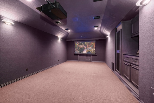 home theater room with visible vents, light carpet, baseboards, and vaulted ceiling