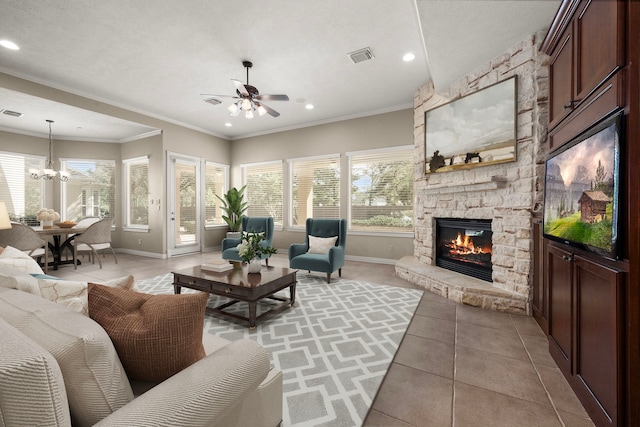 living room featuring visible vents, ornamental molding, a fireplace, light tile patterned floors, and baseboards