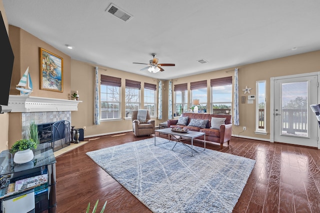 living area featuring dark wood-style floors, ceiling fan, a tiled fireplace, and visible vents