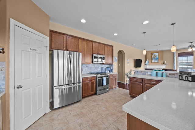 kitchen featuring backsplash, arched walkways, stainless steel appliances, and light countertops