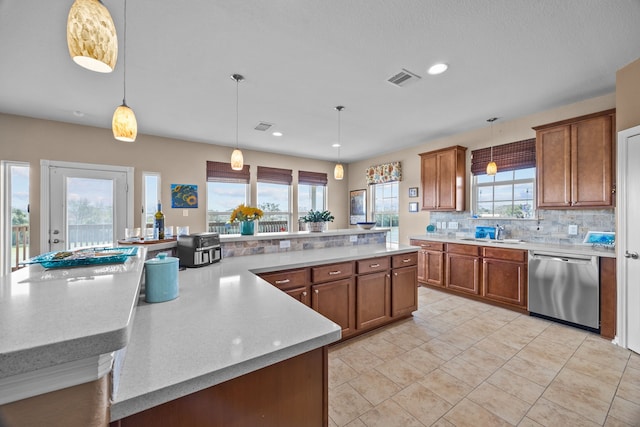 kitchen featuring a sink, decorative backsplash, brown cabinets, and stainless steel dishwasher