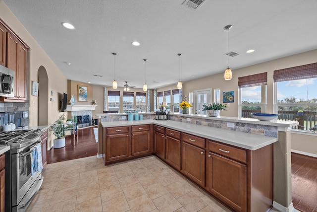 kitchen with visible vents, stainless steel appliances, light countertops, and open floor plan