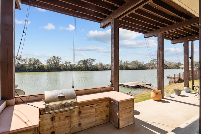 view of patio / terrace featuring exterior kitchen, a dock, a water view, and area for grilling