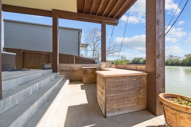 view of patio with a water view, fence, and area for grilling