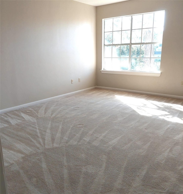 spare room featuring carpet flooring and baseboards