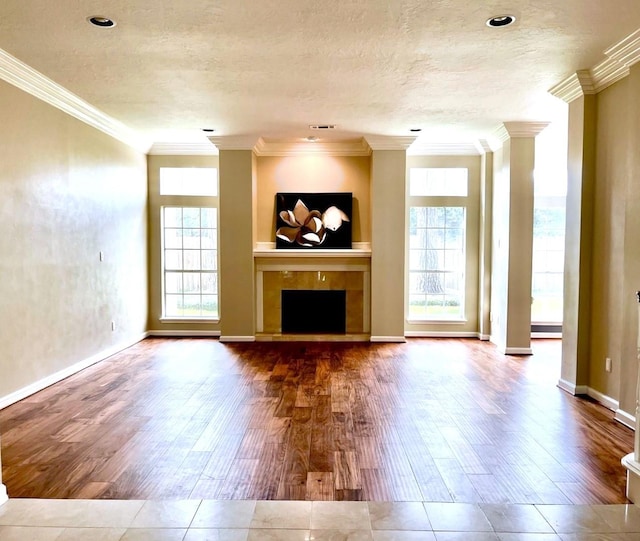 unfurnished living room featuring a textured ceiling, crown molding, wood finished floors, and a tile fireplace