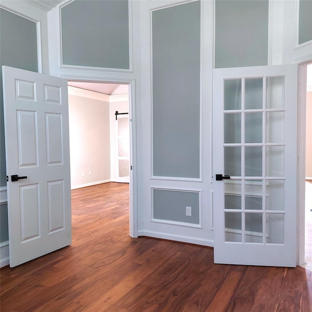 interior space featuring dark wood finished floors, crown molding, and a barn door