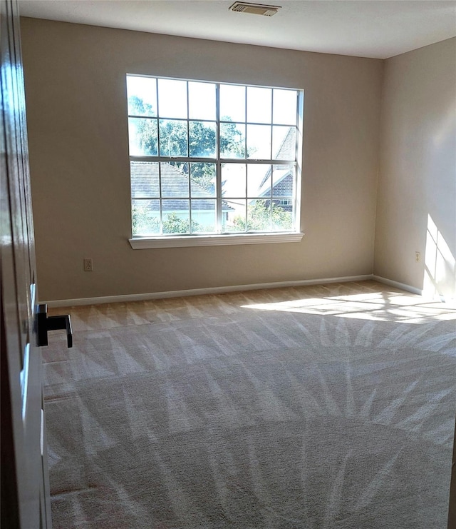 unfurnished room featuring visible vents, light colored carpet, and baseboards