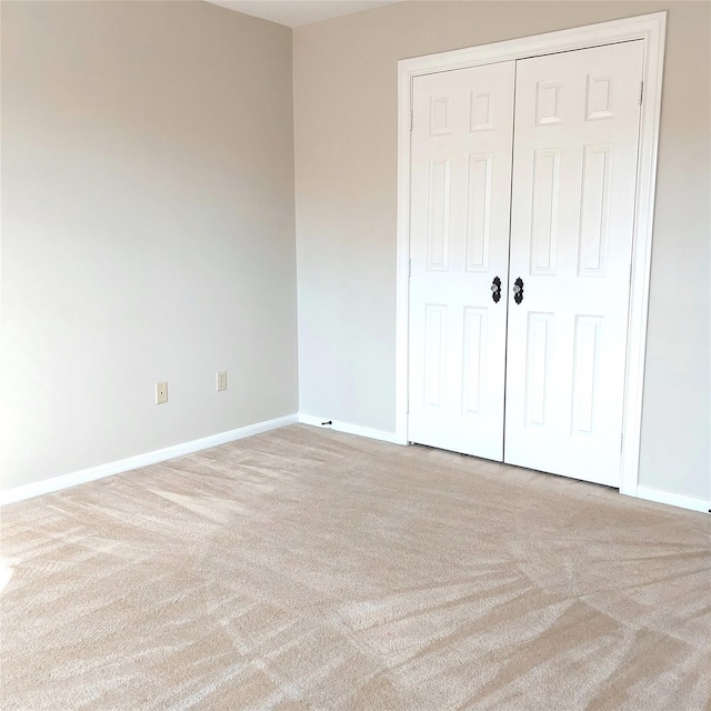 unfurnished bedroom with carpet, baseboards, and a closet