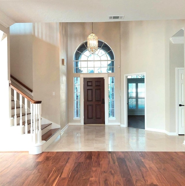 entryway featuring a wealth of natural light, visible vents, stairway, and a notable chandelier