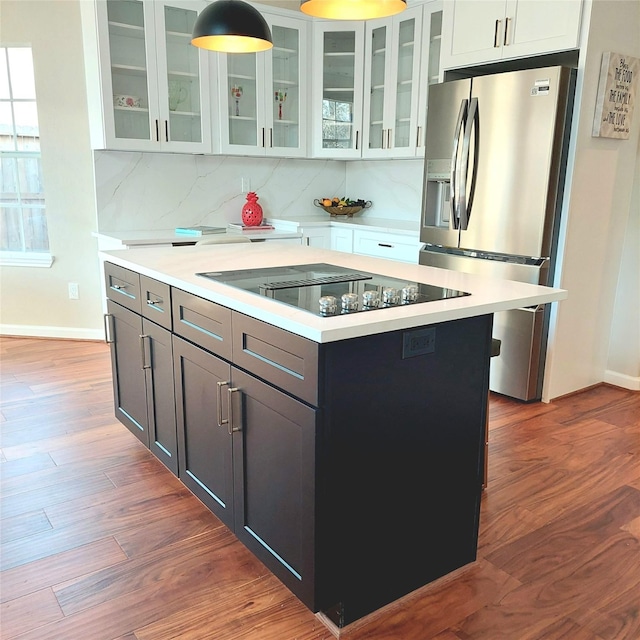 kitchen with wood finished floors, black electric stovetop, stainless steel fridge with ice dispenser, and light countertops