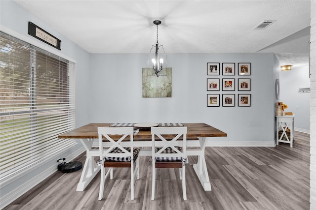 dining area featuring wood finished floors, baseboards, visible vents, breakfast area, and a chandelier