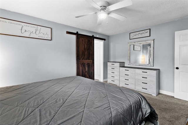 bedroom with a ceiling fan, a textured ceiling, a barn door, carpet flooring, and baseboards