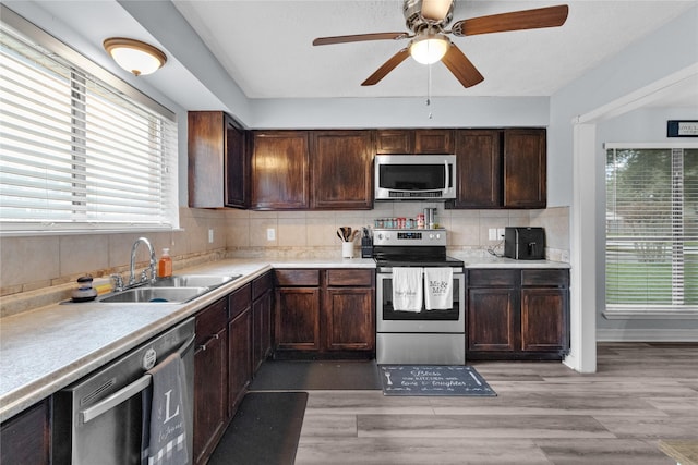 kitchen featuring light wood-type flooring, light countertops, decorative backsplash, appliances with stainless steel finishes, and a sink