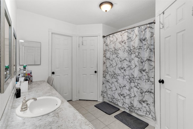 bathroom with a sink, a shower with curtain, double vanity, and tile patterned flooring