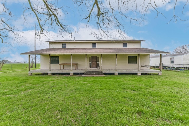 rear view of property with covered porch and a yard