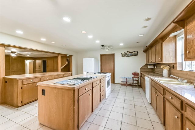 kitchen featuring a center island, light tile patterned flooring, a sink, ceiling fan, and white appliances