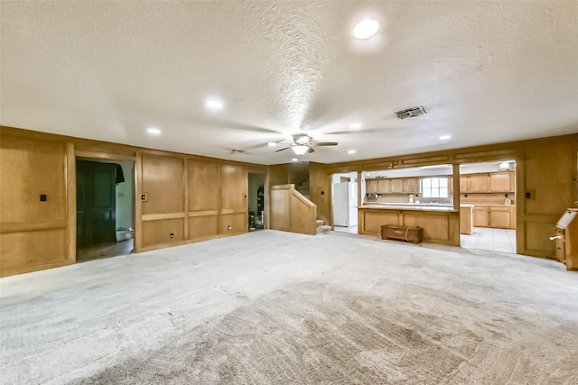 unfurnished living room with visible vents, light colored carpet, stairway, a textured ceiling, and recessed lighting