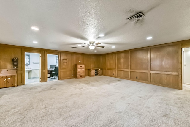 unfurnished room with a textured ceiling, recessed lighting, light carpet, a decorative wall, and visible vents