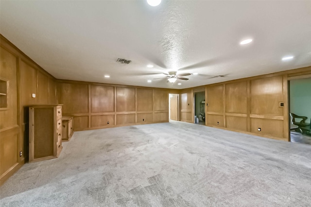 empty room with light colored carpet, visible vents, a decorative wall, and recessed lighting