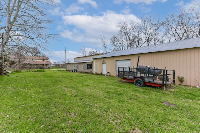 rear view of house with an outbuilding, a lawn, a detached garage, and an outdoor structure