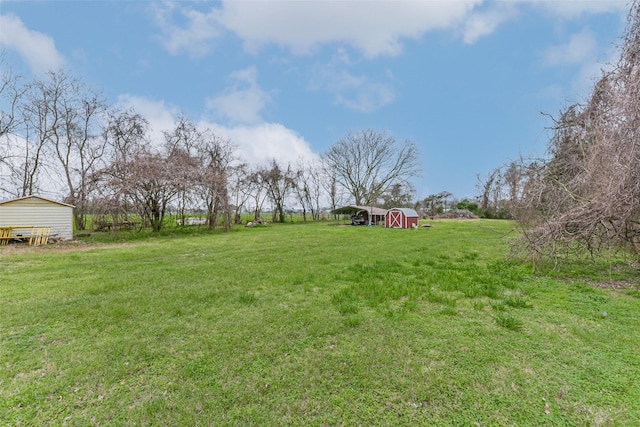 view of yard featuring a storage shed, a rural view, and an outdoor structure