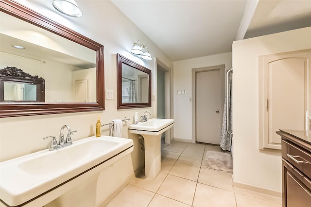 full bath featuring two sinks, baseboards, and tile patterned floors