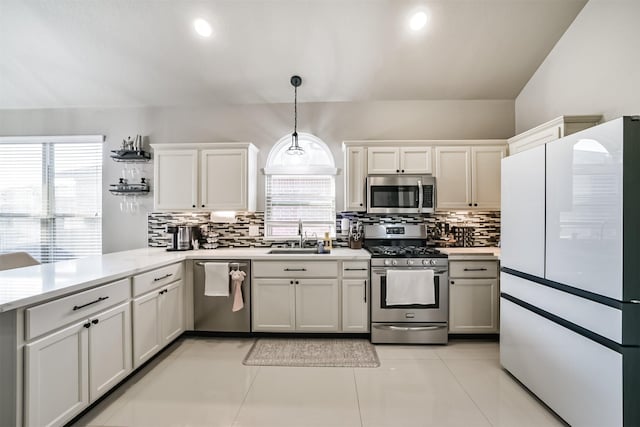 kitchen featuring light countertops, backsplash, appliances with stainless steel finishes, a sink, and a peninsula