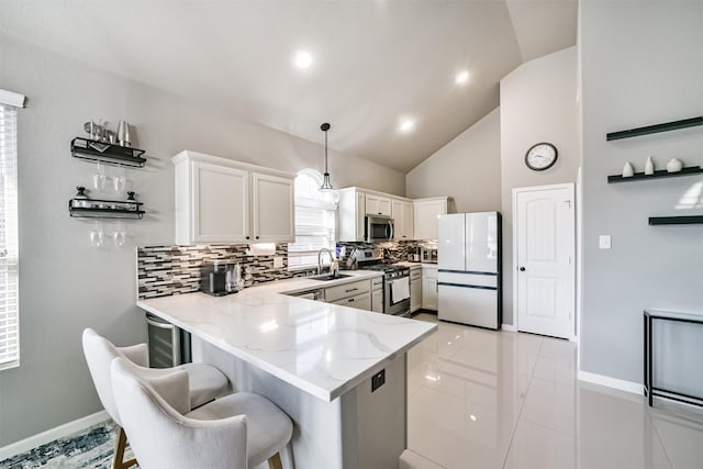 kitchen featuring light stone countertops, stainless steel appliances, a peninsula, a sink, and decorative backsplash