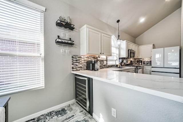 kitchen featuring vaulted ceiling, wine cooler, stainless steel appliances, and backsplash