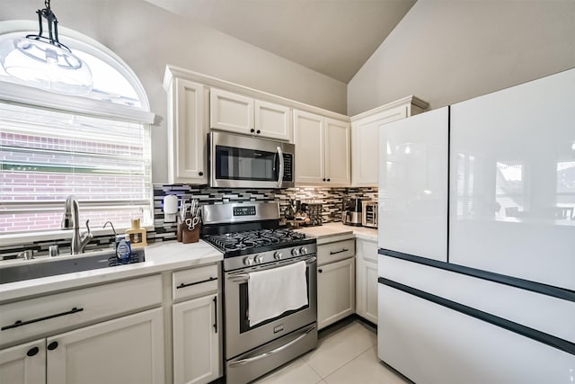 kitchen with decorative backsplash, appliances with stainless steel finishes, vaulted ceiling, white cabinetry, and a sink