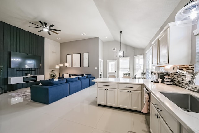 kitchen featuring a peninsula, white cabinets, open floor plan, and a sink