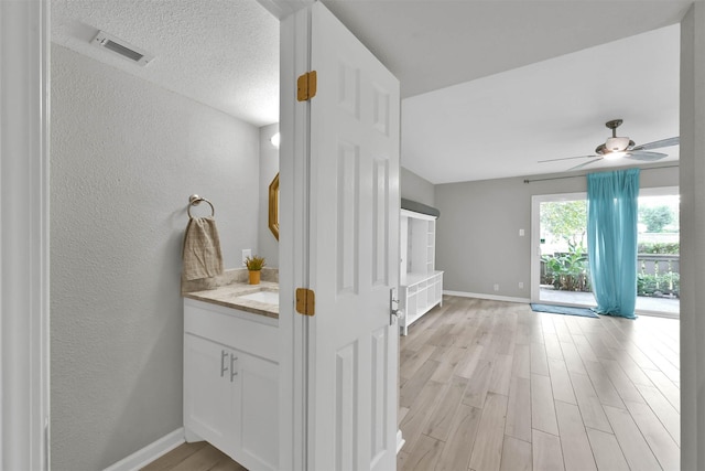 interior space featuring a textured wall, wood finished floors, visible vents, and baseboards