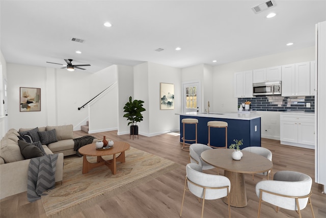 living room with light wood-style flooring, recessed lighting, visible vents, baseboards, and stairway