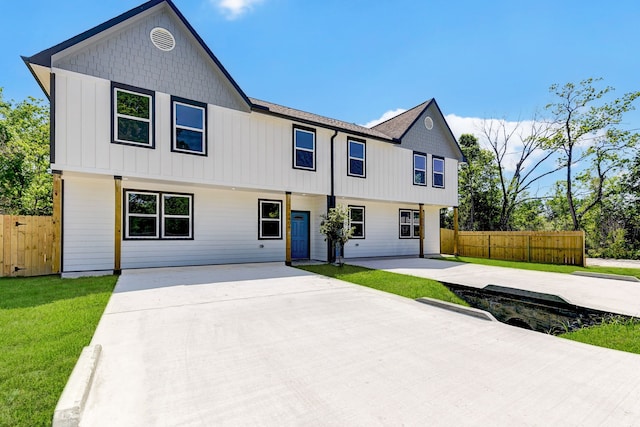 view of front facade featuring a patio area, fence, board and batten siding, and a front yard