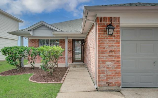 doorway to property with an attached garage, a shingled roof, and brick siding