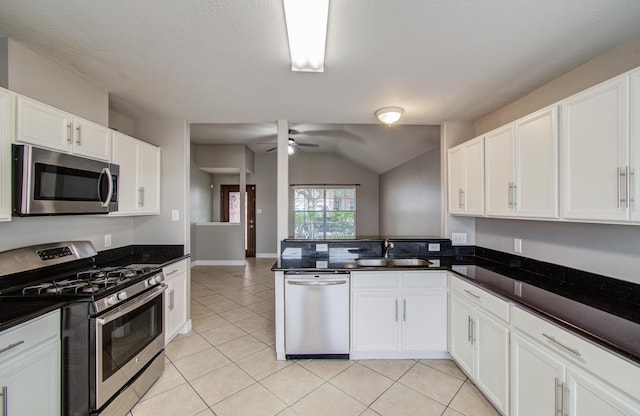 kitchen featuring a peninsula, light tile patterned floors, appliances with stainless steel finishes, and a sink