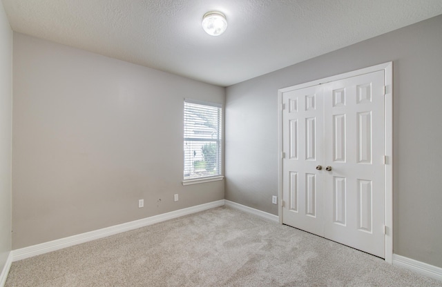 unfurnished bedroom with baseboards, a closet, and light colored carpet