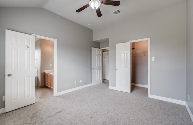 unfurnished bedroom featuring connected bathroom, light colored carpet, visible vents, baseboards, and vaulted ceiling