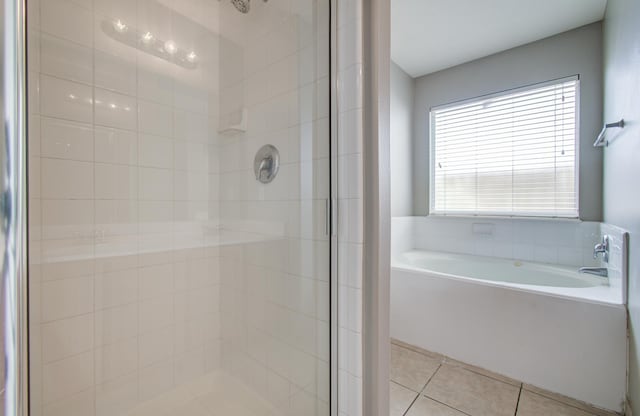 bathroom featuring a stall shower, a bath, and tile patterned floors