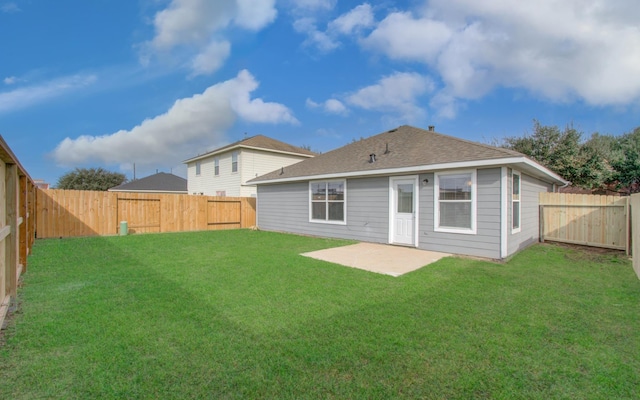 rear view of house with a yard, a shingled roof, a patio, and a fenced backyard