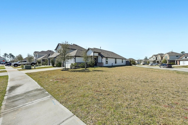 view of front facade with concrete driveway, a front yard, and a residential view