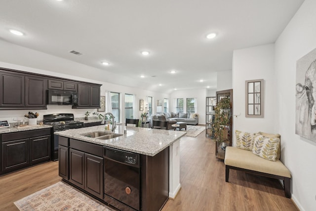 kitchen with black appliances, visible vents, light wood finished floors, and a sink