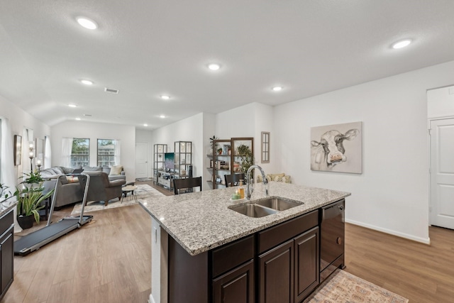 kitchen featuring black dishwasher, light wood finished floors, lofted ceiling, visible vents, and a sink