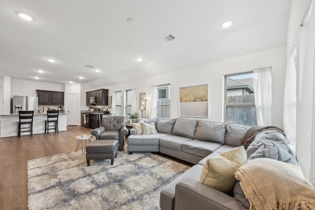 living room with recessed lighting, visible vents, and wood finished floors